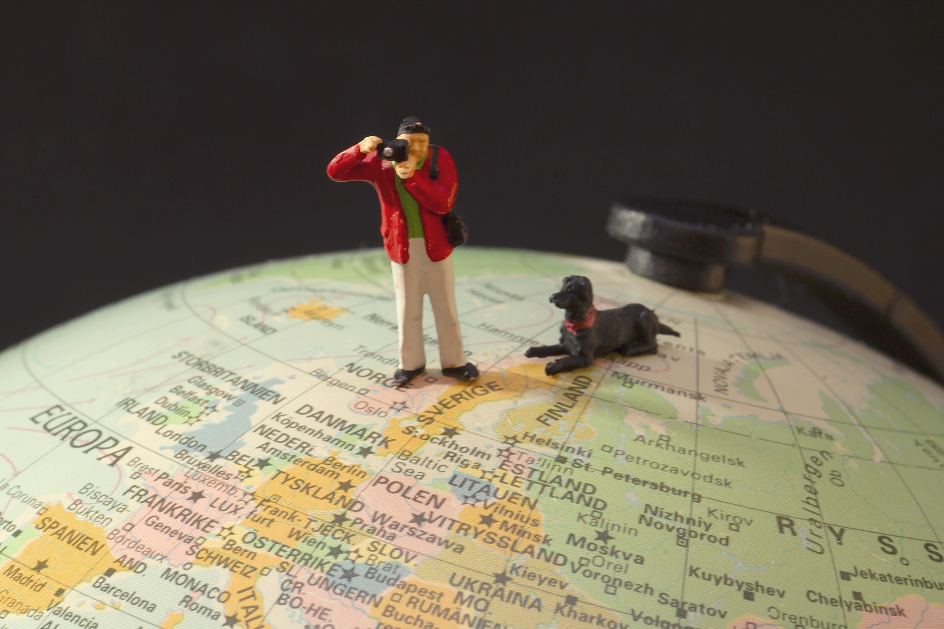 Miniworld - Fotograf med hund står på jordglob.