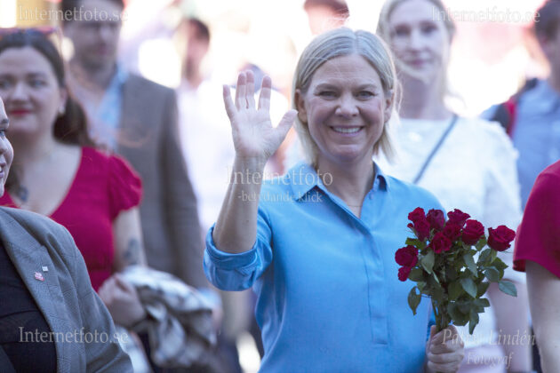 Partiledare Magdalena Andersson ler och vinkar med en bukett r&ouml;da rosor i andra handen f&ouml;rsta maj demonstrationst&aring;g.
